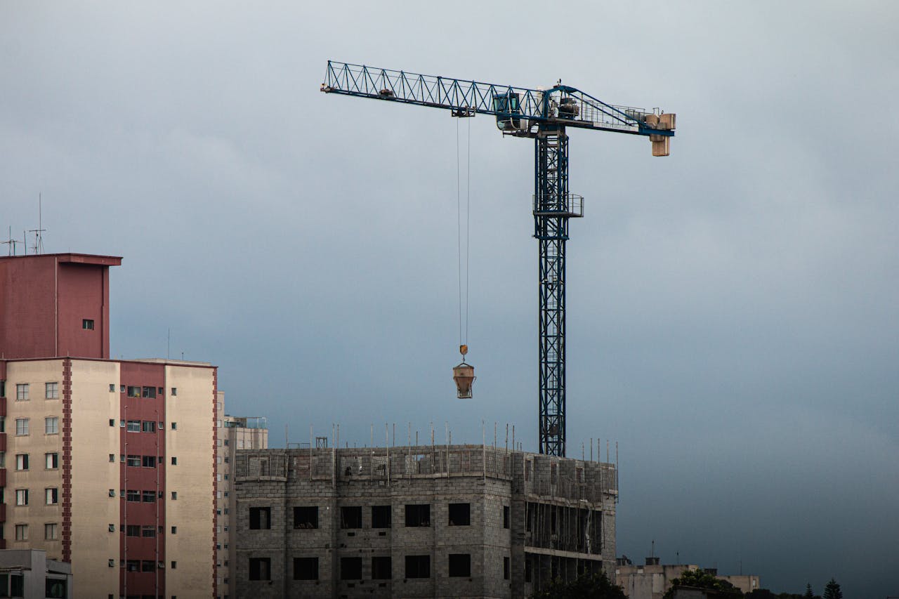 High-rise construction site with a tower crane lifting materials at dusk.