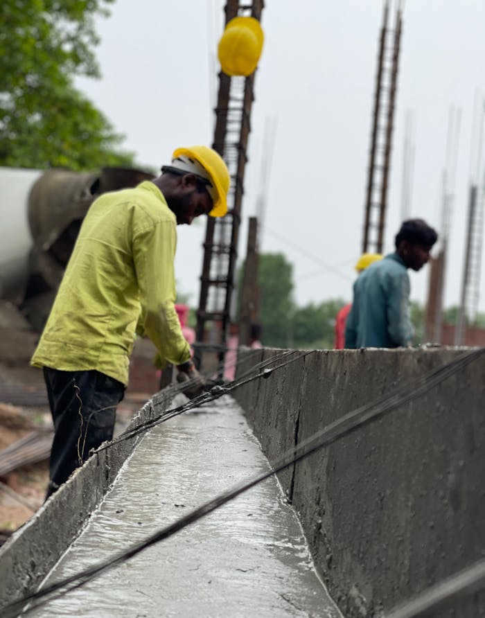 Men at work on a construction site, focusing on concrete tasks, wearing safety gear.