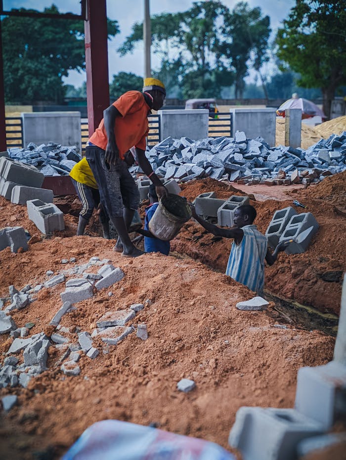Local workers at a construction site handling bricks and materials in Kaduna, Nigeria.