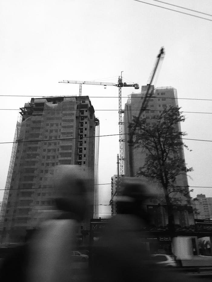 Black and white image of high-rise construction with cranes in urban setting.